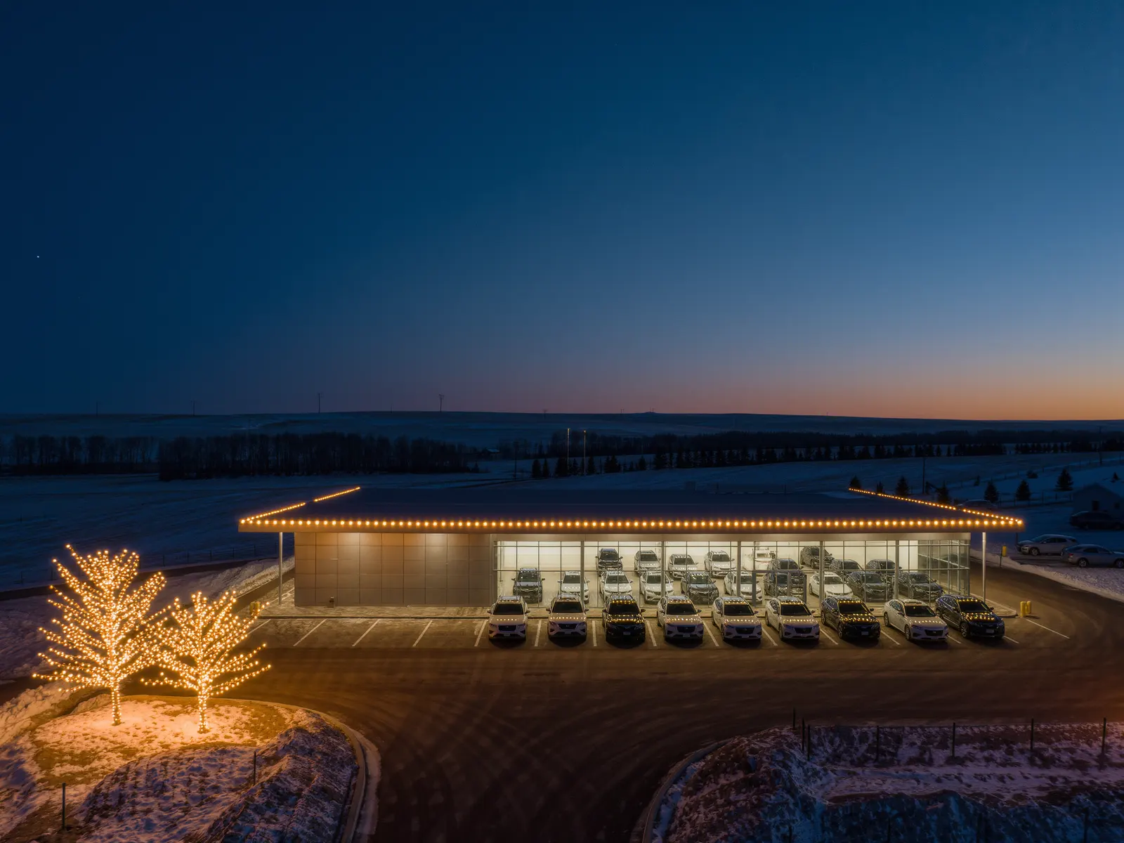 Commercial Christmas light installation along the parapet of a car dealership showroom in Cochrane, Alberta