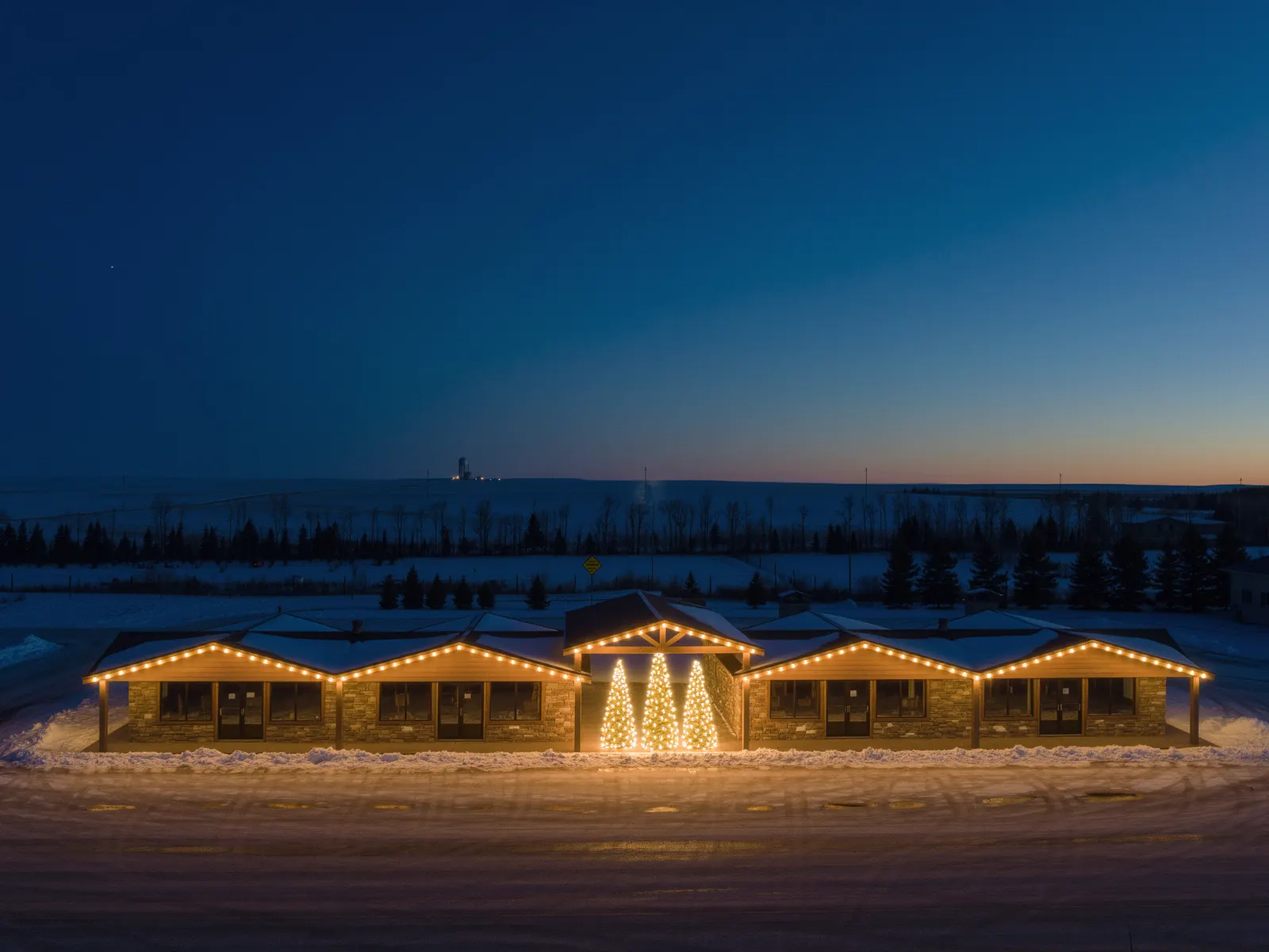 Commercial Christmas lights along the roofline of a timber and stone retail plaza in Cochrane, Alberta
